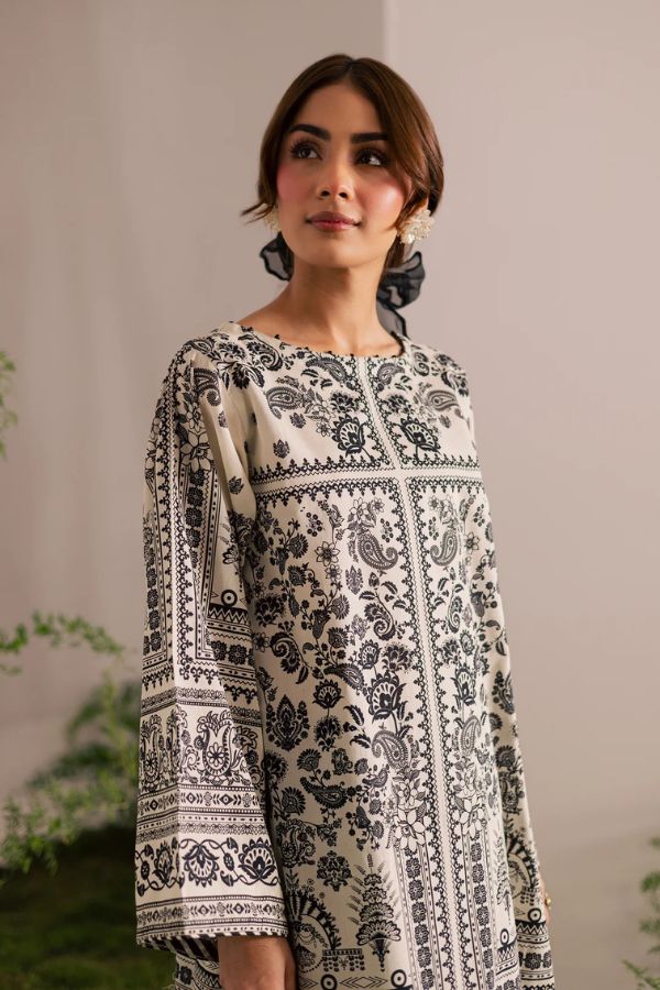 Woman wearing a black and white patterned dress against a neutral background