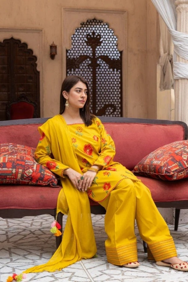 Premium mustard lawn suit by Ragini featuring delicate floral embroidery, embroidered lawn shirt, dyed trousers, and flowing Bamber chiffon dupatta – perfect summer outfit for women in Pakistan, ideal for festive and semi-formal wear.