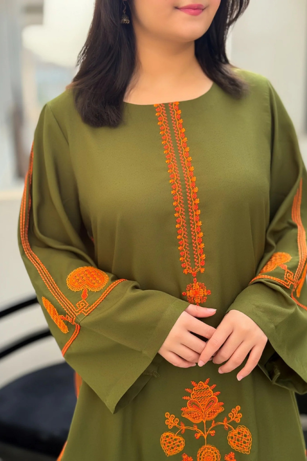 Green dress with orange embroidery worn by a person indoors