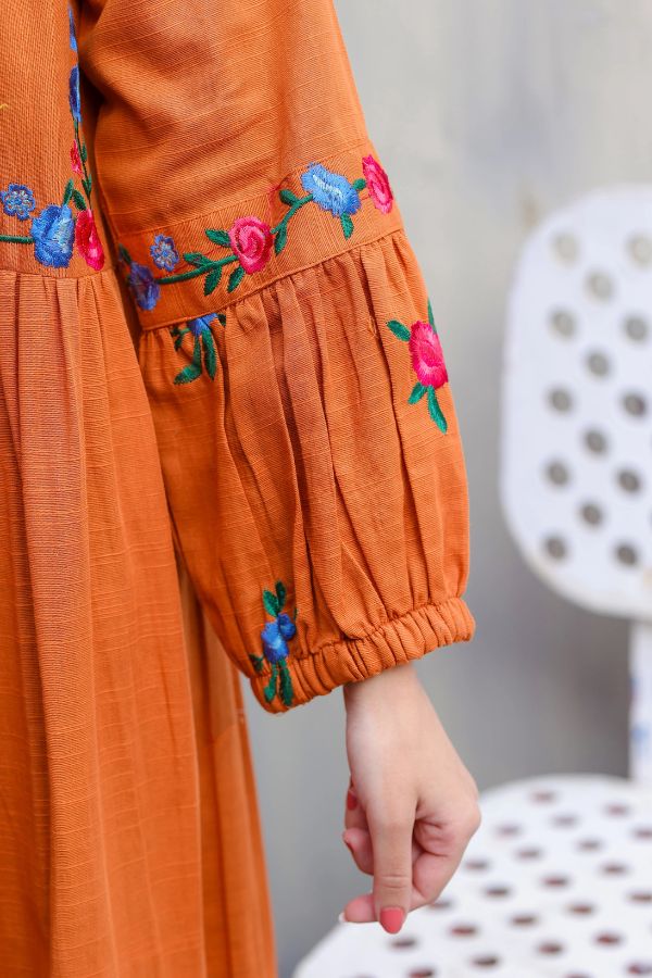 Orange dress with floral embroidery on a blurred background
