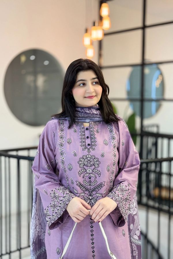 Woman wearing a purple embroidered traditional outfit in an indoor setting.