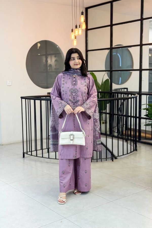 Woman in a purple outfit holding a white handbag in an indoor setting.