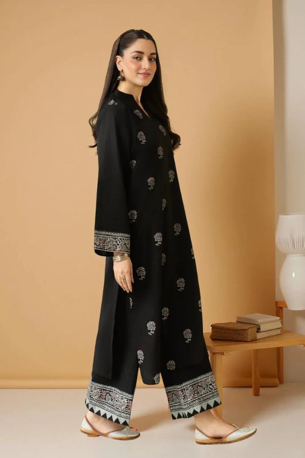 Woman wearing a black traditional outfit with white patterns against a beige background