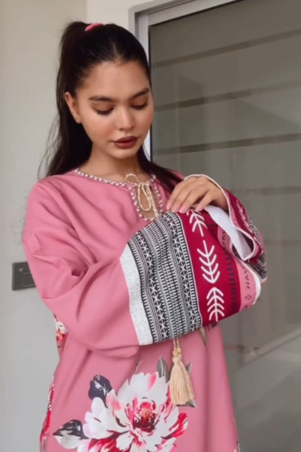 Woman in a pink dress holding a patterned handbag.