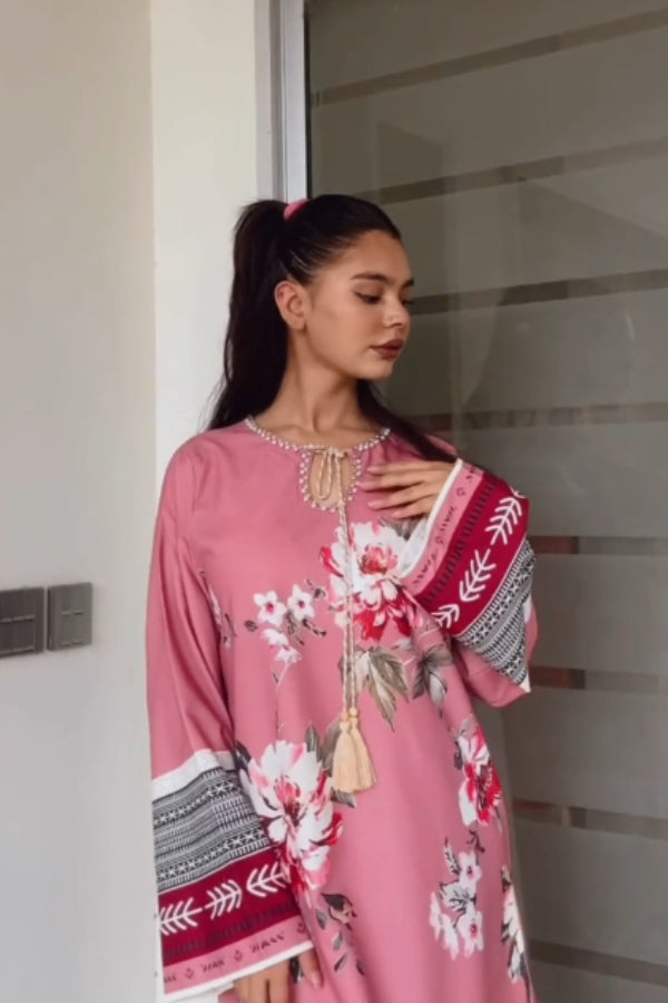 Woman wearing a pink floral dress with a patterned sleeve, standing indoors.