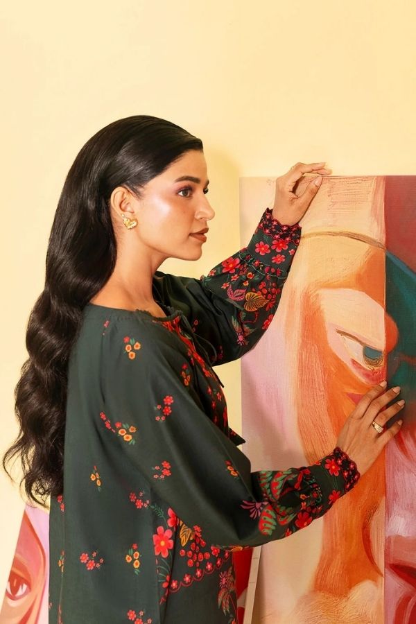 Woman in a floral dress looking at a painting on a beige wall