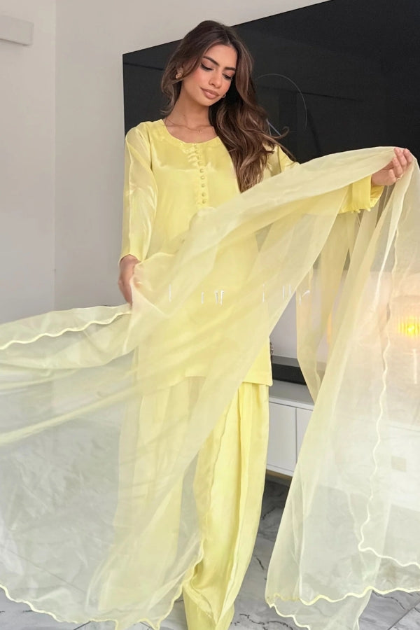 Woman in a yellow traditional outfit with a flowing dupatta in an indoor setting.