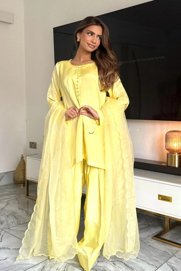 Woman in a yellow outfit standing in a modern living room.