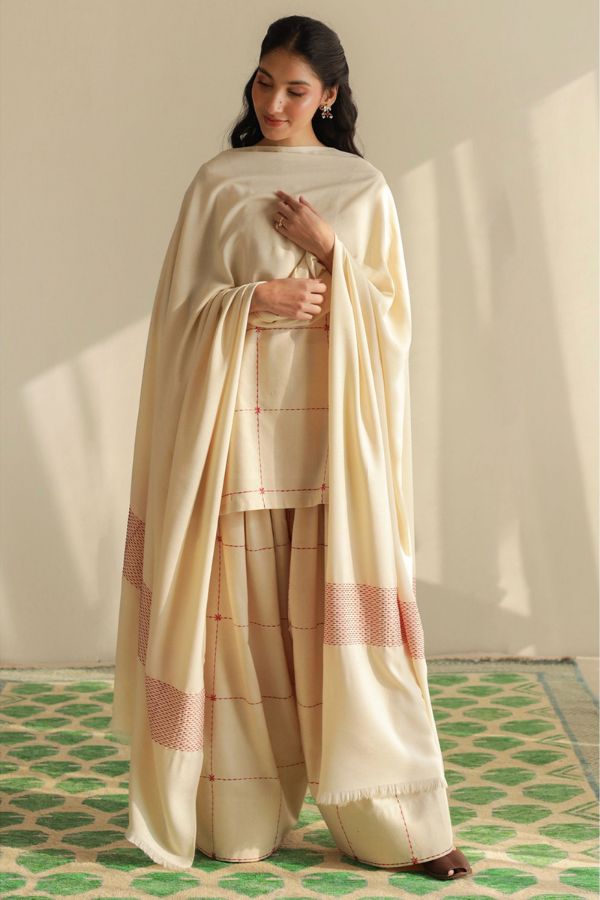 Woman wearing a traditional outfit with a beige dupatta on a patterned floor.