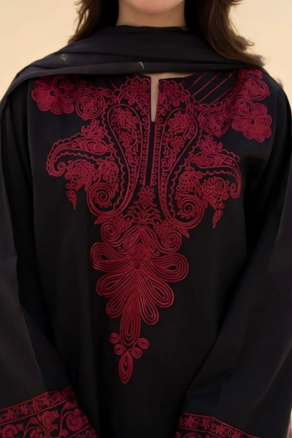 Black garment with red intricate embroidery on a beige background