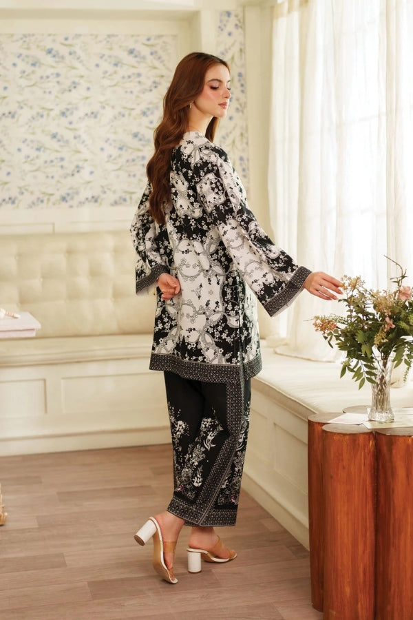 Woman in a floral outfit standing in a room with floral wallpaper and a wooden table.