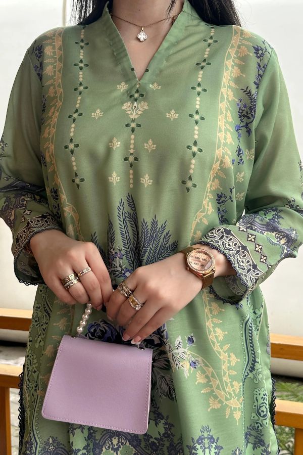 Person wearing a green embroidered outfit holding a purple clutch.