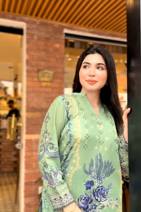 Woman wearing a green floral dress standing in front of a store entrance.