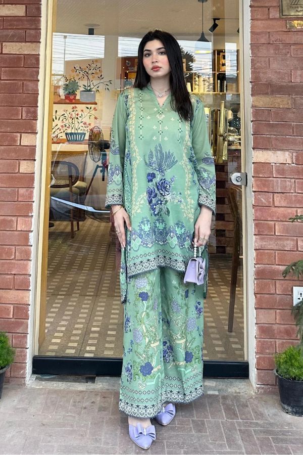 Woman wearing a green floral outfit standing in front of a door.