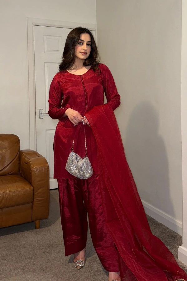 Woman in a red outfit standing in a room with a brown leather chair and white door.