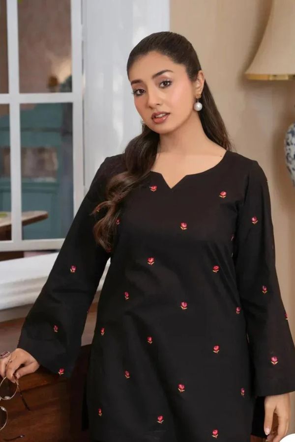 Woman wearing a black dress with red patterns indoors