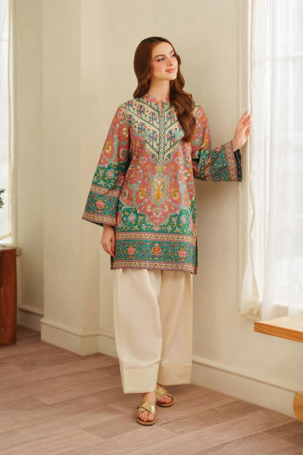 Woman wearing a colorful embroidered traditional outfit in a room with light-colored walls and wooden floor.
