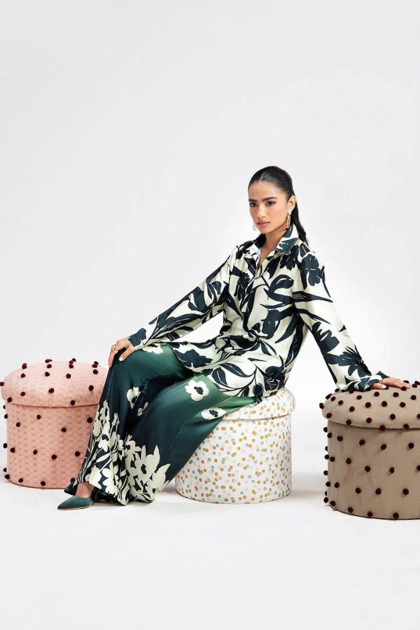 Woman in a floral dress sitting on a polka dot ottoman with a white background