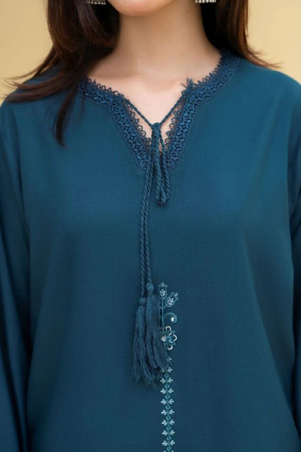 Teal blouse with lace detailing and tassel on a beige background