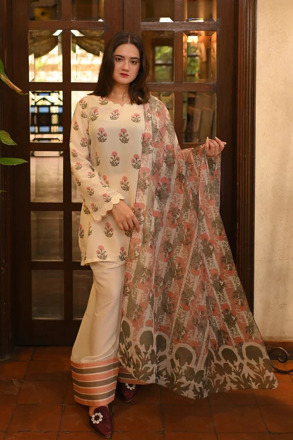 Woman holding a floral dupatta in front of a wooden door