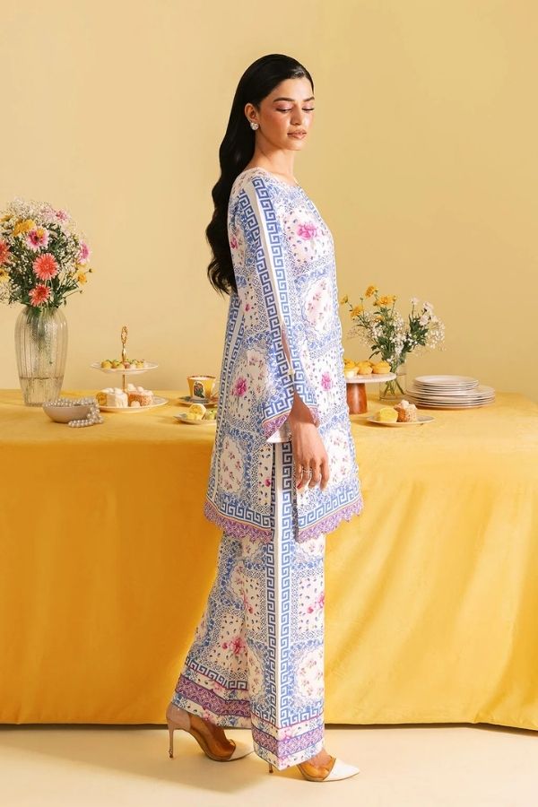 Woman in a patterned outfit standing by a table with yellow tablecloth and floral decorations.