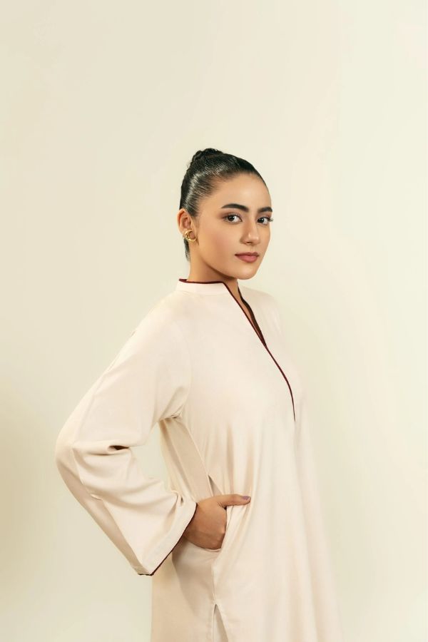 Woman wearing a light-colored outfit against a plain background