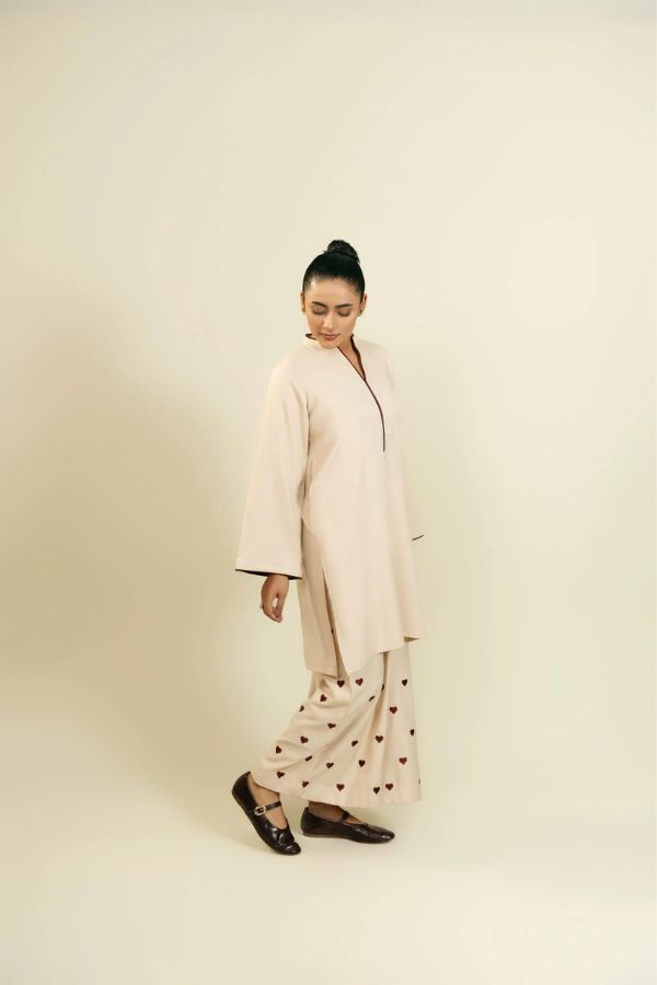 Woman wearing a long beige coat with a plain background