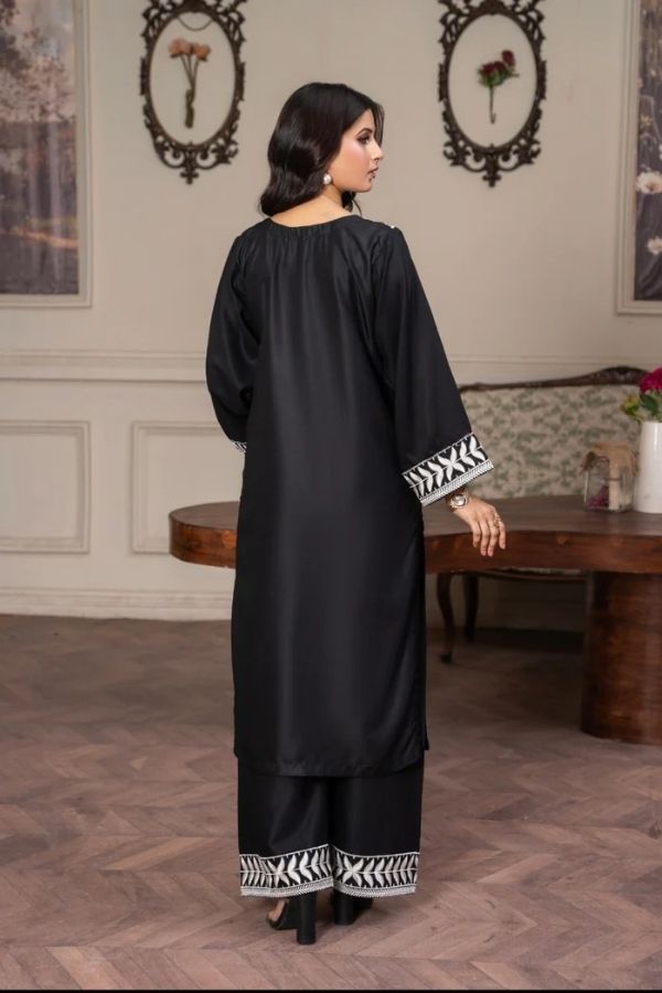 Woman wearing a black outfit with white patterns in an elegant room.