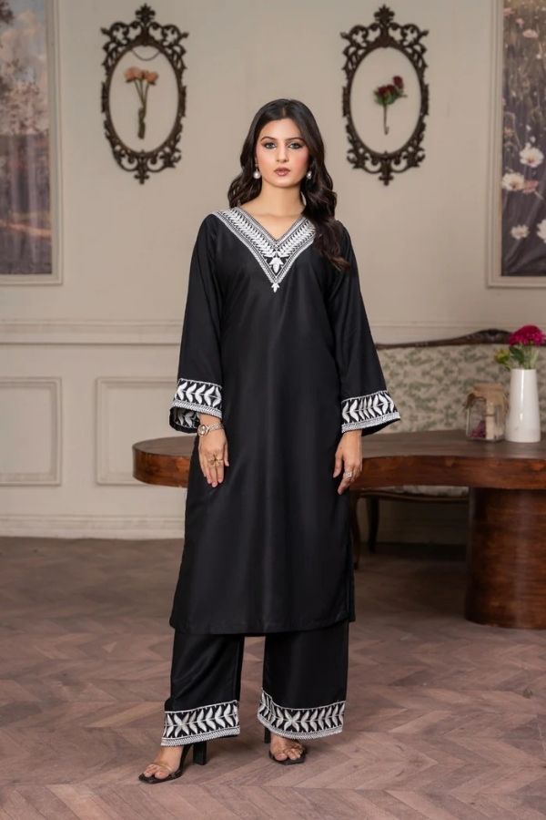 Woman wearing a black traditional outfit with white embroidery in an elegant room.