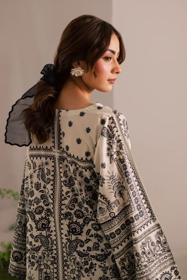 Woman wearing a black and white patterned dress against a neutral background