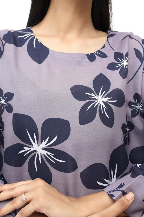 Close-up of a person wearing a purple blouse with floral patterns.