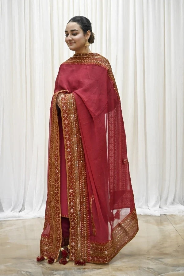 Premium maroon 3-piece festive stitched suit for women – featuring golden hand embroidery, gota work, mirror embellishments, and an embroidered chiffon dupatta with tassels – traditional Pakistani outfit perfect for Eid, mehndi, and formal events.