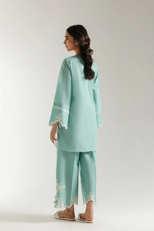 Woman wearing a light blue traditional outfit with floral embroidery on a white background