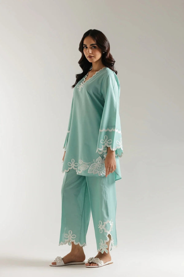 Woman wearing a light blue outfit with white lace details on a white background