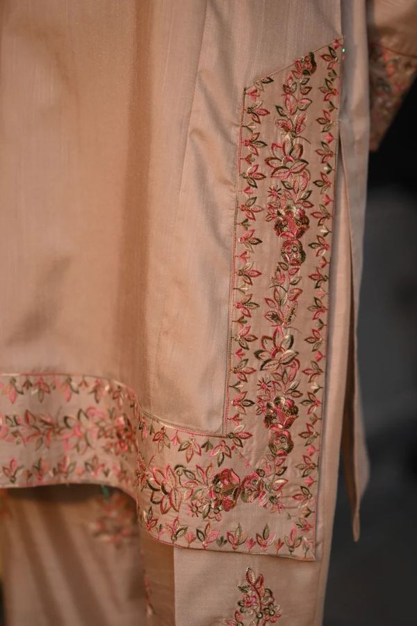 Close-up of a beige garment with intricate floral embroidery on a blurred background