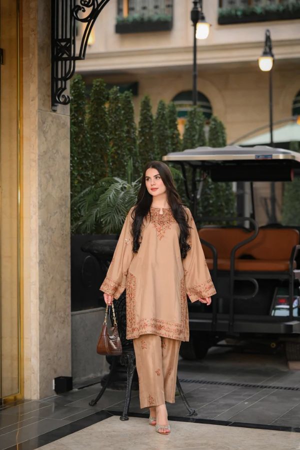 Woman in a beige traditional outfit standing outside a building with greenery and a golf cart in the background.