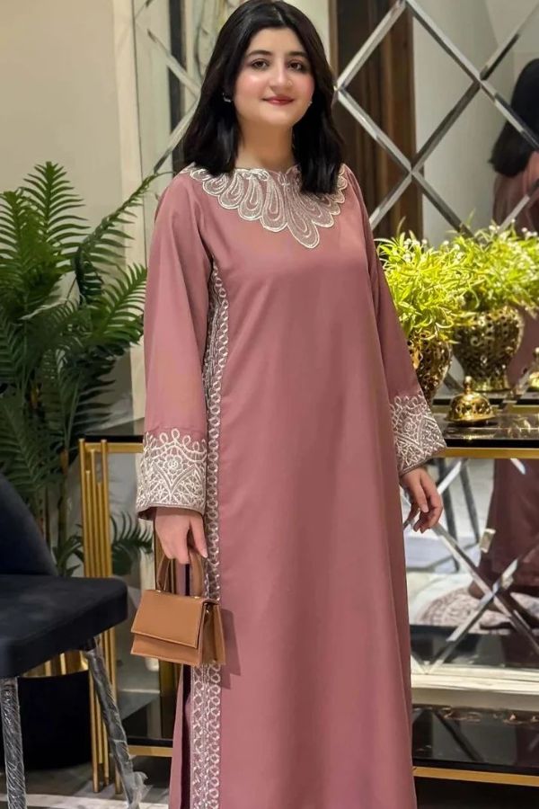 Woman wearing a pink dress with white lace details in an indoor setting.