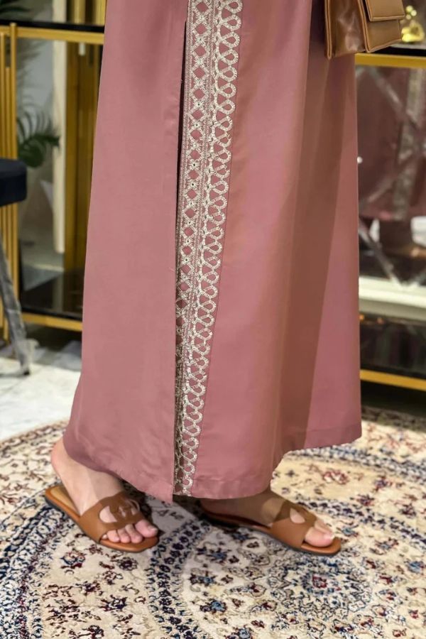 Pink pants with lace trim worn by a person, standing on a patterned rug.