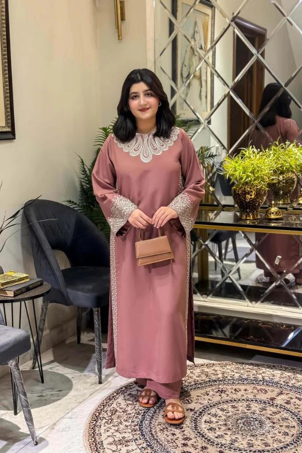Woman in a pink dress standing in an elegant room with decor elements.