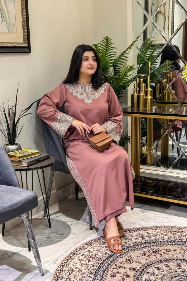 Woman in a pink dress sitting on a chair in a room with decor elements.