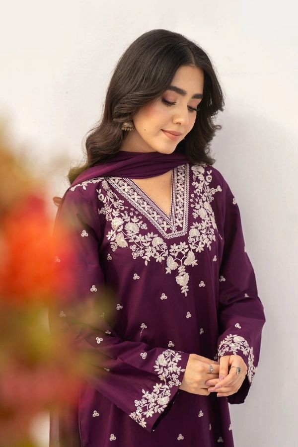 Woman wearing a purple embroidered outfit with a plain background