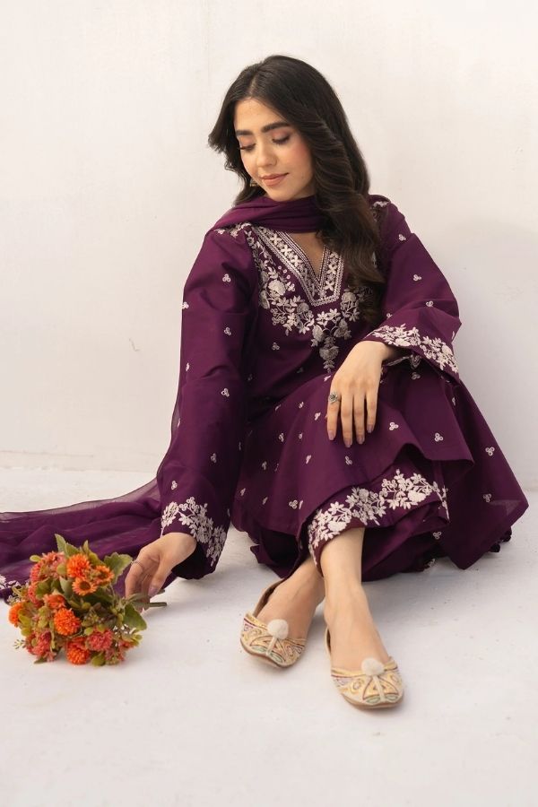 Woman in a purple traditional outfit with floral patterns on a white background
