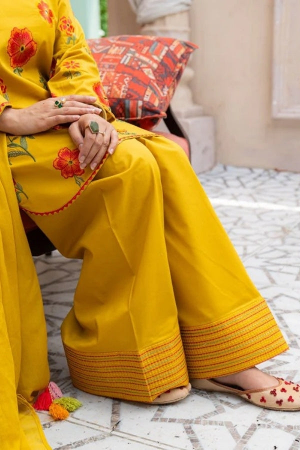 Premium mustard lawn suit by Ragini featuring delicate floral embroidery, embroidered lawn shirt, dyed trousers, and flowing Bamber chiffon dupatta – perfect summer outfit for women in Pakistan, ideal for festive and semi-formal wear.