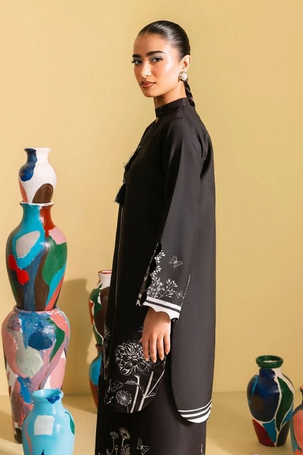 Woman in a black outfit standing next to colorful vases against a beige wall