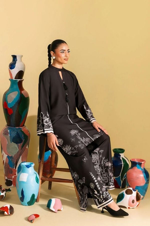 Woman in a black outfit sitting among colorful vases on a beige background