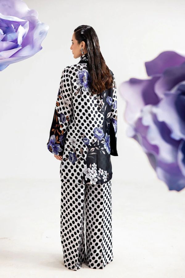 Woman wearing a polka dot outfit with floral details, surrounded by purple flowers on a white background