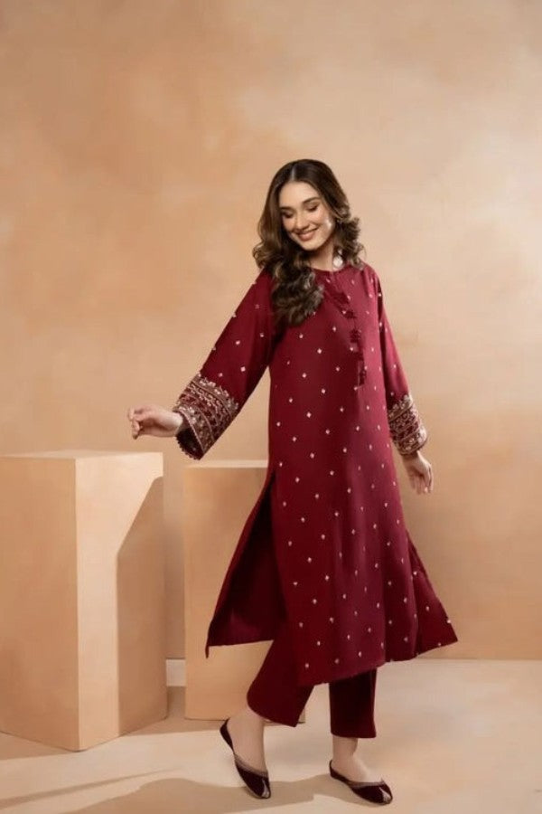 Woman wearing a maroon traditional outfit with white patterns against a beige background