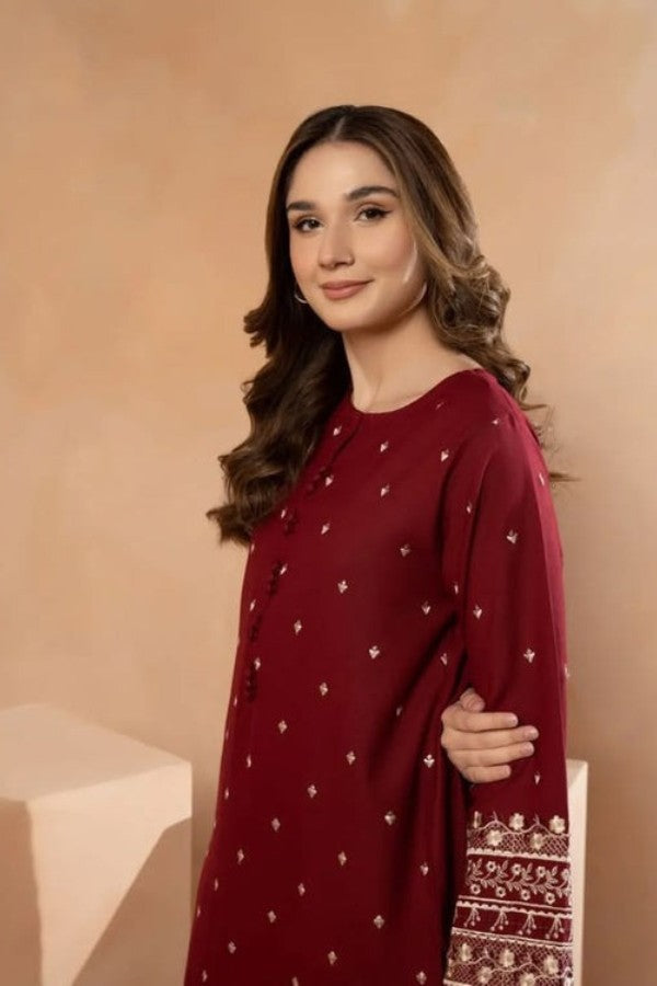 Woman wearing a red traditional outfit with white patterns against a beige background