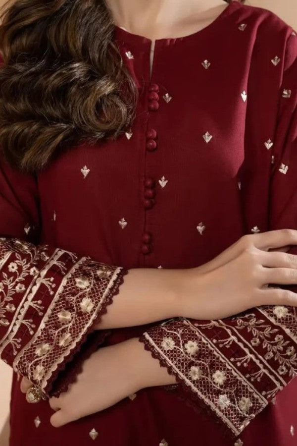 Red embroidered garment with intricate patterns on sleeves and neckline.