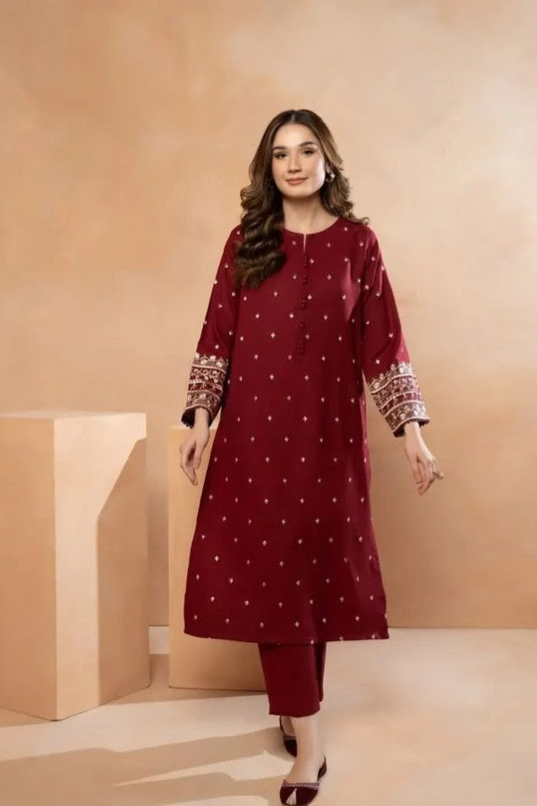 Woman wearing a maroon traditional outfit with white patterns on a beige background